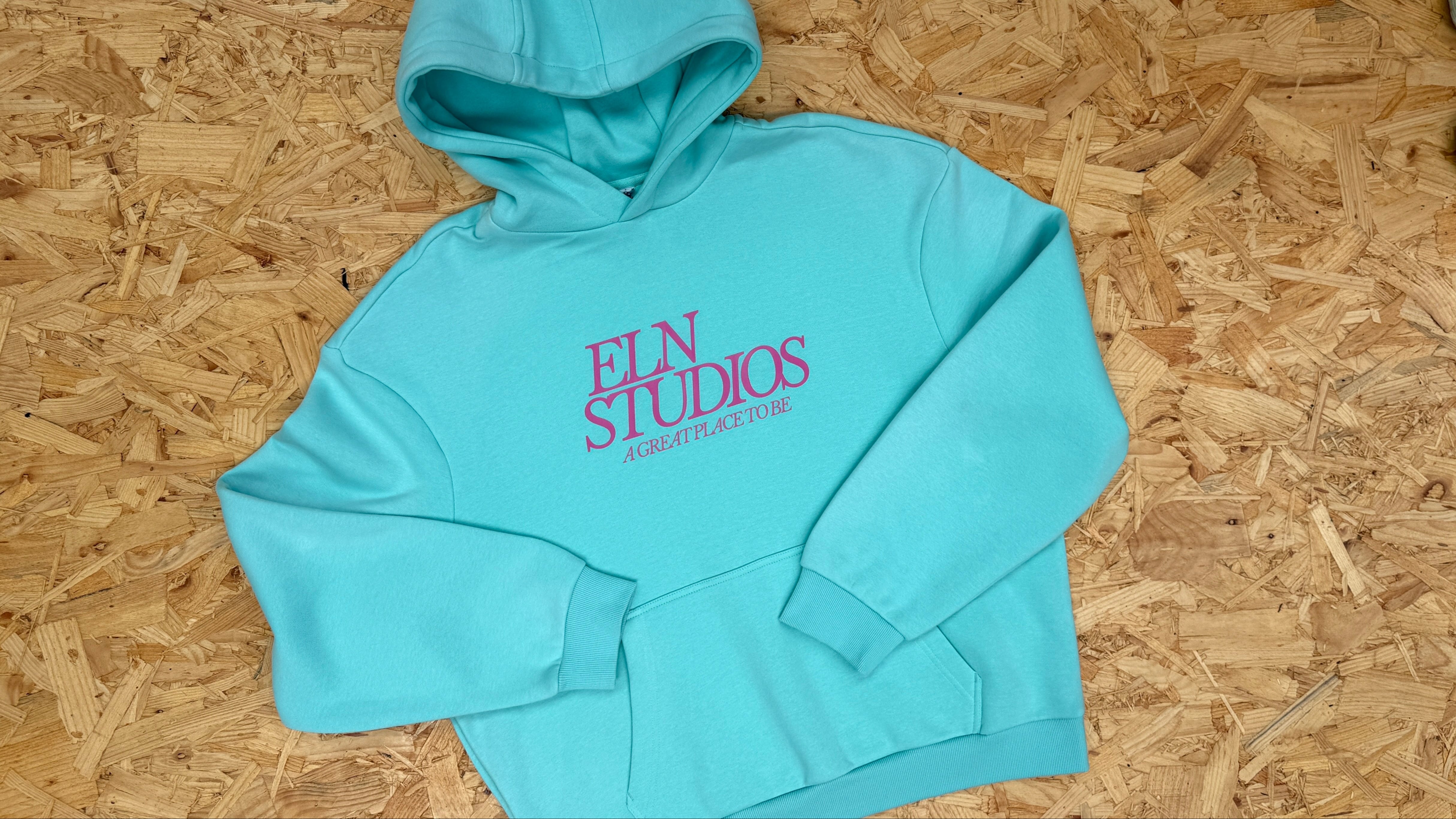 Light blue hoodie with 'ELN STUDIOS' text on a wooden table